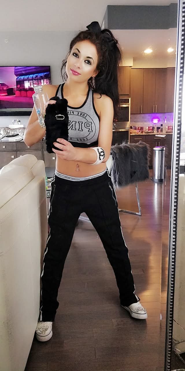 Jennifer Jorgensen Ahmed at home in a grey tank top and black track pants holding a water bottle